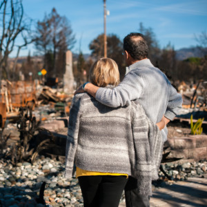 Photo of a man and woman looking at their destroyed home.