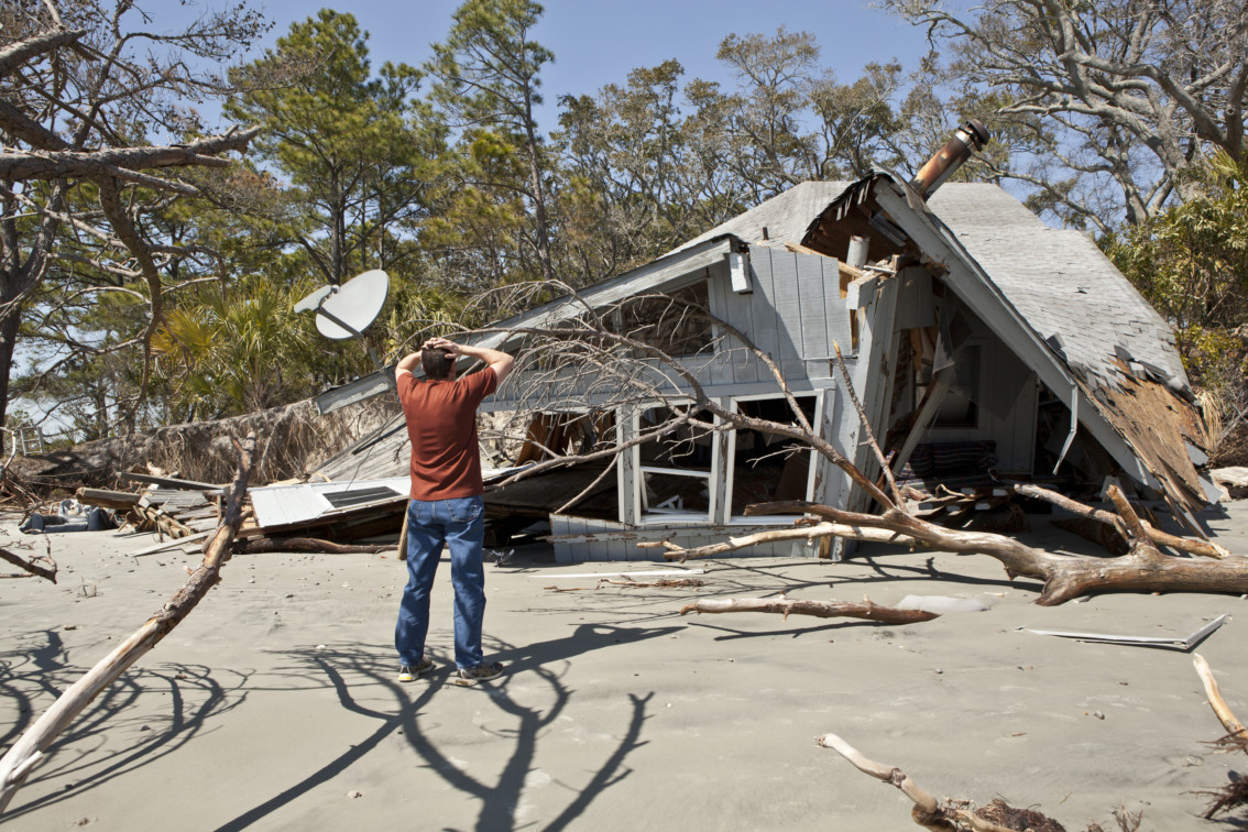 Photo of man grieving over house destroyed in flood.